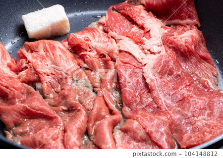 A cooking scene where beef (thinly sliced) is baked in a frying pan. 104148812
