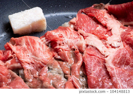 A cooking scene where beef (thinly sliced) is baked in a frying pan. 104148813
