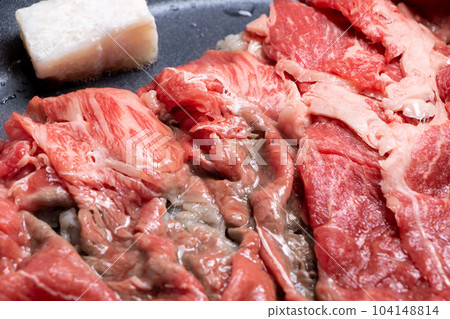 A cooking scene where beef (thinly sliced) is baked in a frying pan. 104148814