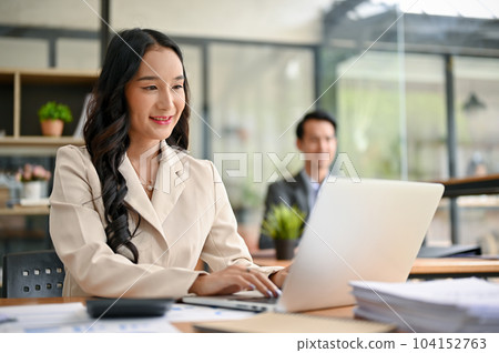 A beautiful Asian businesswoman using her laptop to manage his tasks, working at her desk 104152763