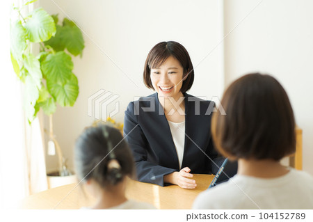 A woman in a suit having a conversation with her parent and child 104152789
