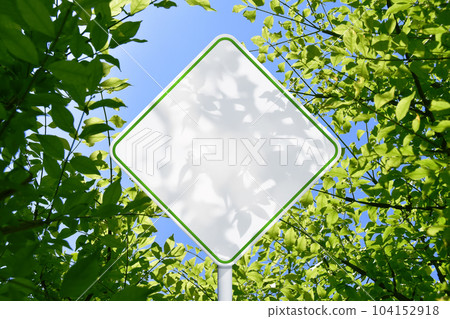 A white sign like a road sign against the background of young leaves A white sign like a road sign against the background of young leaves 104152918