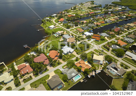 Aerial view of residential suburbs with private homes located on gulf coast near wildlife wetlands with green vegetation on sea shore. Living close to nature concept 104152967