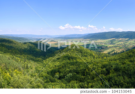 Aerial view of mountain hills covered with dense green lush woods on bright summer day. 104153045