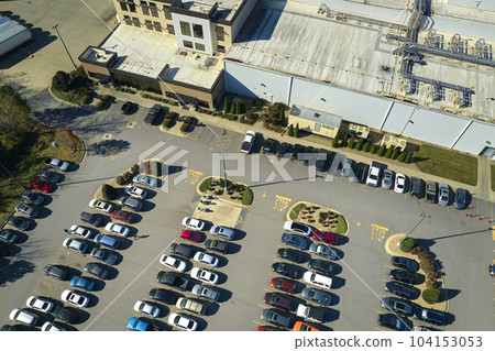Aerial view of many employee cars parked on parking lot in front of industrial factory building Aerial view of many employee cars parked on parking lot in front of industrial factory building 104153053