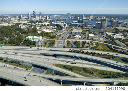 Aerial view of Jacksonville city with high office buildings and american freeway intersection with fast driving cars and trucks. View from above of USA transportation infrastructure Aerial view of Jacksonville city with high office buildings and american freeway intersection with fast driving cars and trucks. View from above of USA transportation infrastructure 104153098