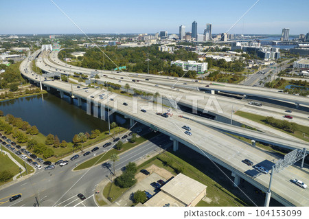 Aerial view of Jacksonville city with high office buildings and american freeway intersection with fast driving cars and trucks. View from above of USA transportation infrastructure Aerial view of Jacksonville city with high office buildings and american freeway intersection with fast driving cars and trucks. View from above of USA transportation infrastructure 104153099