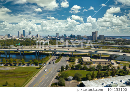 Aerial view of Jacksonville city with high office buildings and american freeway intersection with fast driving cars and trucks. View from above of USA transportation infrastructure 104153100