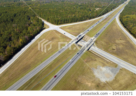 Aerial view of freeway overpass junction with fast moving traffic cars and trucks in american rural area. Interstate transportation infrastructure in USA Aerial view of freeway overpass junction with fast moving traffic cars and trucks in american rural area. Interstate transportation infrastructure in USA 104153171