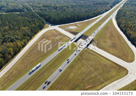 Aerial view of freeway overpass junction with fast moving traffic cars and trucks in american rural area. Interstate transportation infrastructure in USA 104153173