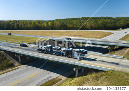 Aerial view of freeway overpass junction with fast moving traffic cars and trucks in american rural area. Interstate transportation infrastructure in USA 104153177
