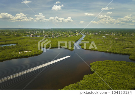 Aerial view of Florida wetlands with small motorboat swimming between green vegetation in water inlets. Recreation in nature concept 104153184