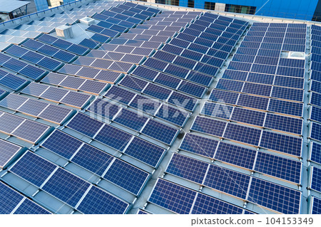 Aerial view of blue photovoltaic solar panels mounted on industrial building roof for producing green ecological electricity. Production of sustainable energy concept 104153349