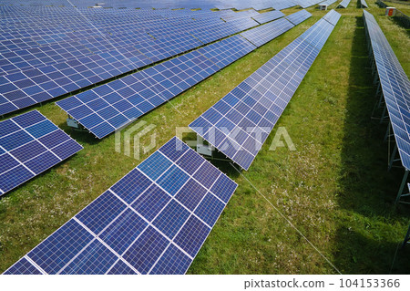 Aerial view of big sustainable electric power plant with many rows of solar photovoltaic panels for producing clean electrical energy. Renewable electricity with zero emission concept 104153366