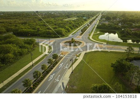 Aerial view of american suburban area with rural road roundabout intersection with moving cars traffic. Circular transportation crossroads in Florida 104153818