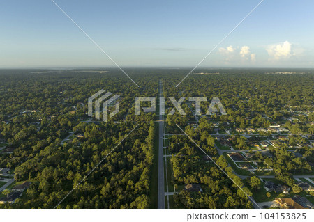 Aerial view of american small town in Florida with private homes between green palm trees and suburban streets in quiet residential area Aerial view of american small town in Florida with private homes between green palm trees and suburban streets in quiet residential area 104153825