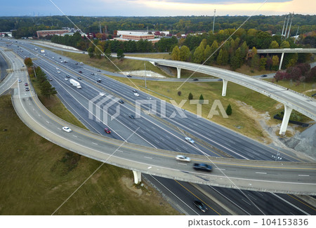 Aerial view of american freeway intersection with fast moving cars and trucks. USA transportation infrastructure concept Aerial view of american freeway intersection with fast moving cars and trucks. USA transportation infrastructure concept 104153836