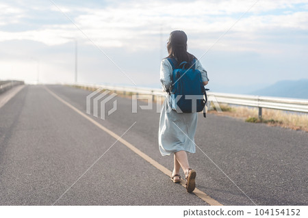 Rear view of woman traveler with backpack walking on road japanese mood with blue sky 104154152