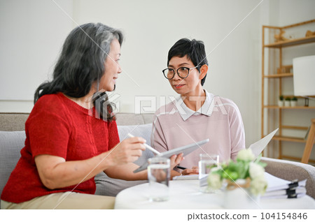 A middle-aged Asian female health insurance agent visited a retired woman at home. A middle-aged Asian female health insurance agent visited a retired woman at home. 104154846