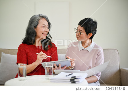 A middle-aged Asian female health insurance agent visited a retired woman at home. 104154848