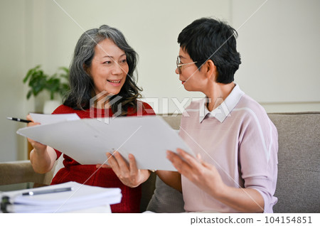 A middle-aged Asian female health insurance agent visited a retired woman at home A middle-aged Asian female health insurance agent visited a retired woman at home 104154851