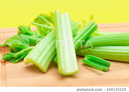Fresh Celery Stem and Chopped Celery Sticks on Wooden Cutting Board 104155228