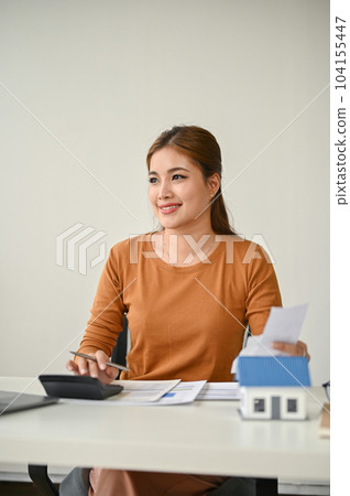 A female real estate agent working on a letter of guarantee for her clients at her desk. A female real estate agent working on a letter of guarantee for her clients at her desk. 104155447