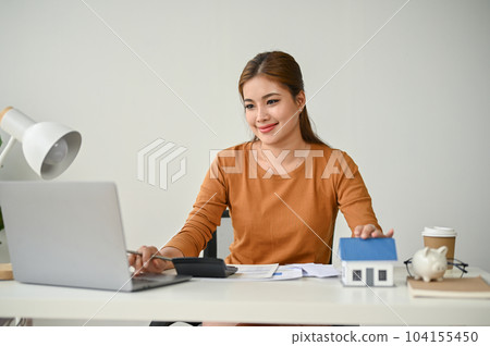 A beautiful Asian female real estate agent working at her desk, using her laptop 104155450