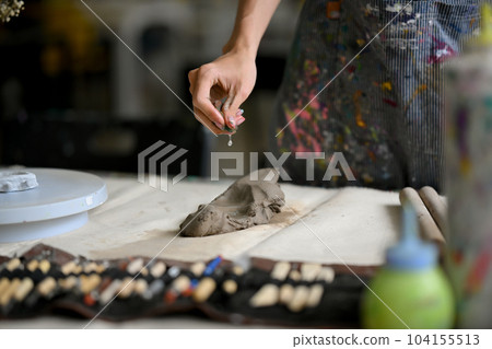 Close-up image of a male artist potter kneading raw clay to make an earthenware at his worktable Close-up image of a male artist potter kneading raw clay to make an earthenware at his worktable 104155513