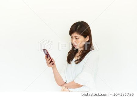 A woman with a grim expression looking at her smartphone A woman with a grim expression looking at her smartphone 104155786