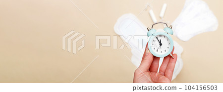 Women's hygiene pads with tampons and alarm clock on beige background Women's hygiene pads with tampons and alarm clock on beige background 104156503