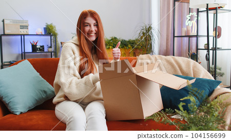 Happy young woman shopper unpacking cardboard box delivery parcel online shopping purchase at home 104156699