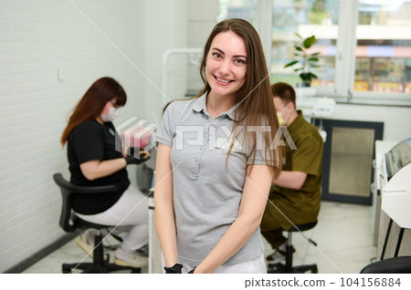 Portrait of Caucasian young female dentist doctor, dental hygienist, maxillofacial surgeon, orthodontist smiling looking at camera, standing in the dental examination room of a modern dentistry clinic 104156884