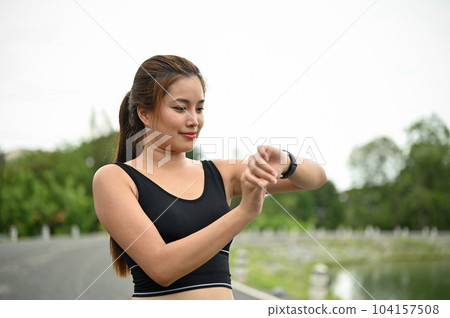 An Asian woman in sportswear checking her calories burned on her smartwatch An Asian woman in sportswear checking her calories burned on her smartwatch 104157508