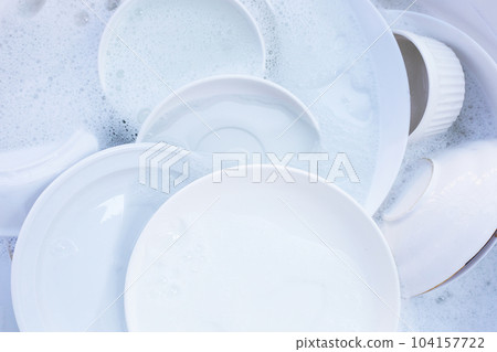 Dishes and bowls in water and bubbles of dishwashing liquid 104157722