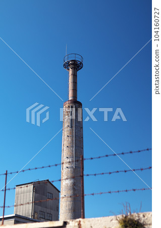 A factory chimney rises in the blue sky 104160727