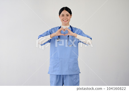 A positive female doctor making a heart shape hand sign. A positive female doctor making a heart shape hand sign. 104160822