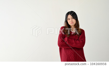 Pretty Asian woman stands against an isolated white background with her arms crossed. who cares Pretty Asian woman stands against an isolated white background with her arms crossed. who cares 104160938