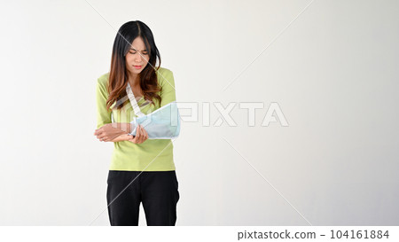 A sad and painful young Asian woman with her accidentally broken arm in an arm sling 104161884