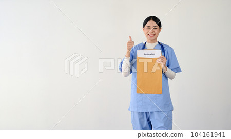 A cheerful Asian female doctor holding a resignation letter and showing her thumb up A cheerful Asian female doctor holding a resignation letter and showing her thumb up 104161941