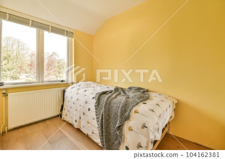 a bedroom with yellow walls and hardwood flooring, showing the light coming in through the large window panes 104162381
