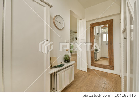 a hallway with wood flooring and a clock hanging on the wall above the door to the entranceway area a hallway with wood flooring and a clock hanging on the wall above the door to the entranceway area 104162419