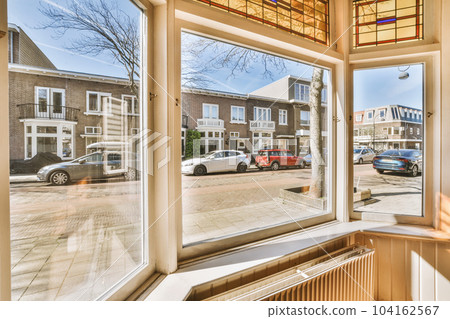 a window with cars parked in the street and buildings on both sides, as seen from an outside looking out 104162567