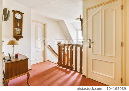 a room with an old clock on the wall and red carpeted floor in front of the door to another room a room with an old clock on the wall and red carpeted floor in front of the door to another room 104162989