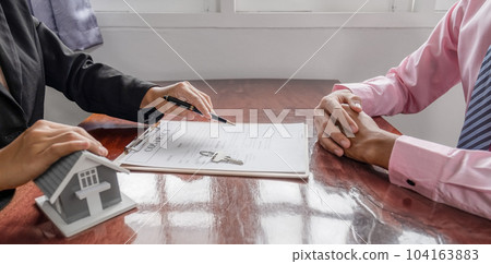 hand. The real estate agent explains the business contract 104163883