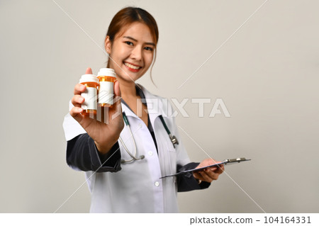 Friendly smiling doctor holding bottles of pills with a blank white label isolated on white background 104164331