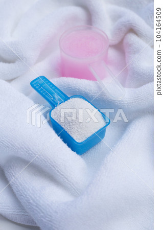 Detergent powder and fabric softener in measuring spoon on towel. Laundry concept. 104164509