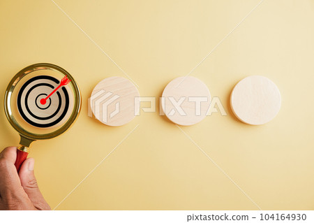 A magnifier glass magnifying a target board, emphasizing importance of hitting business objectives. Against with copy space, it symbolizes the pursuit of innovation and charting a winning path. A magnifier glass magnifying a target board, emphasizing importance of hitting business objectives. Against with copy space, it symbolizes the pursuit of innovation and charting a winning path. 104164930