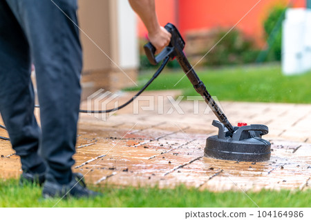 machine cleaning stone pavement in front of the house with a brush 104164986