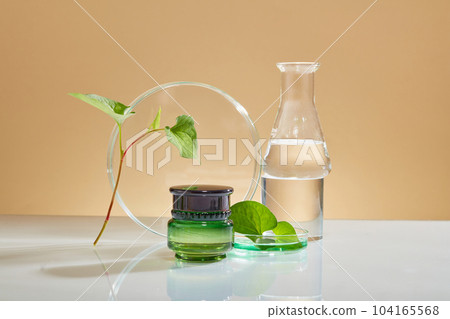 Unbranded jar decorated with petri dish and conical flask with few fish mint. Container packaging of skin care branding extracted from Fish mint (Houttuynia cordata) 104165568